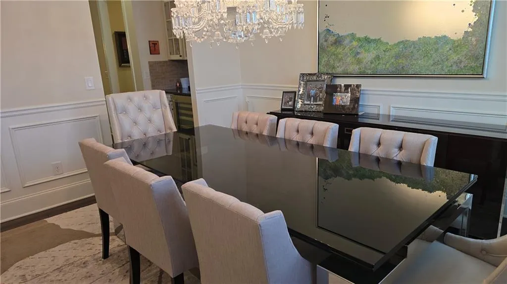 Dining area with a wainscoted wall, a notable chandelier, and a decorative wall