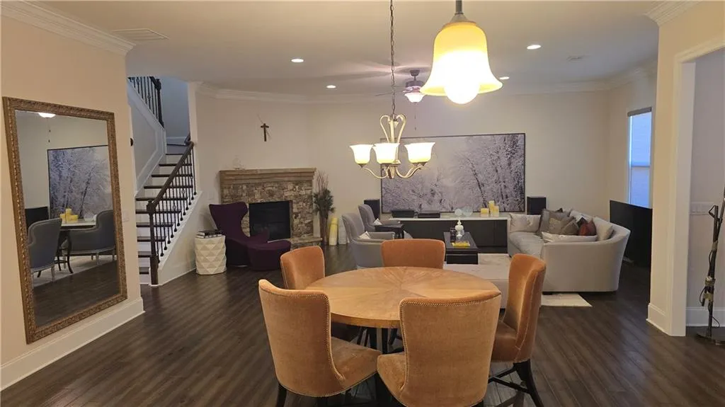 Dining room with crown molding, dark wood finished floors, stairs, a fireplace, and an inviting chandelier