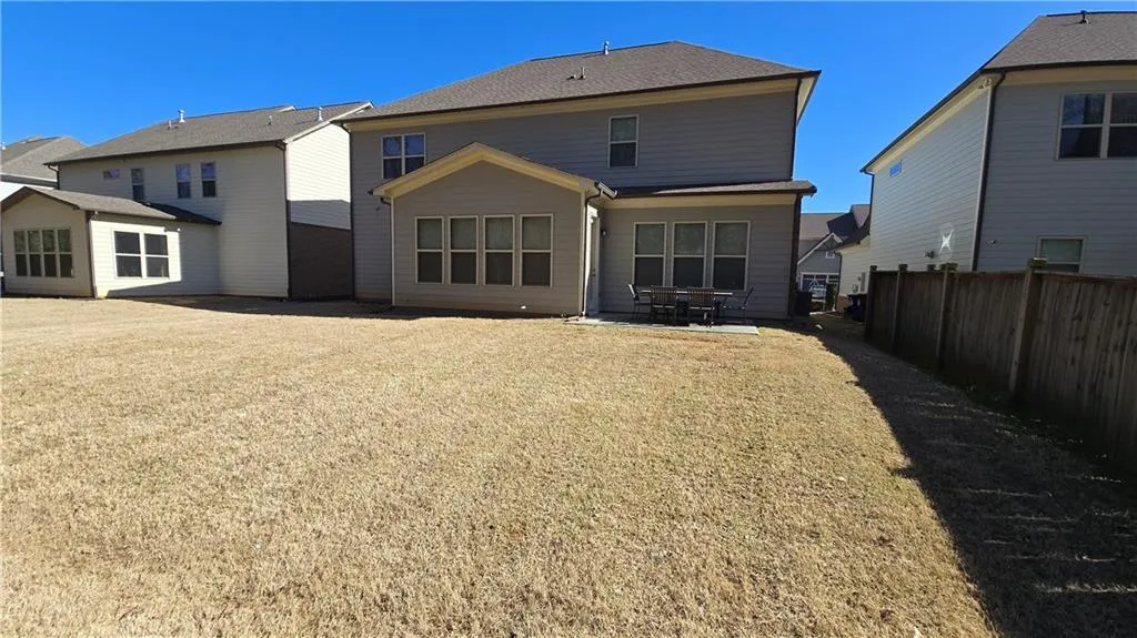 Rear view of house featuring a yard, a patio area, and fence