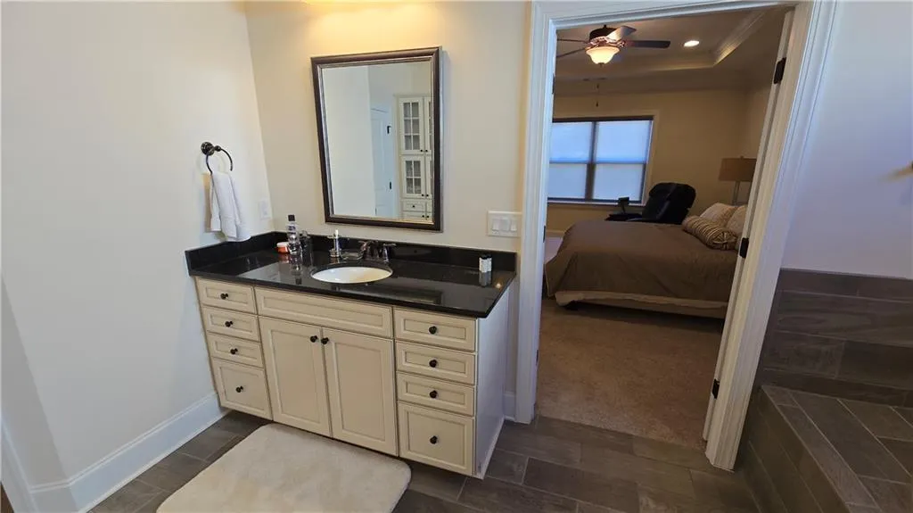 Bathroom featuring baseboards, ceiling fan, vanity, ornamental molding, and ensuite bath