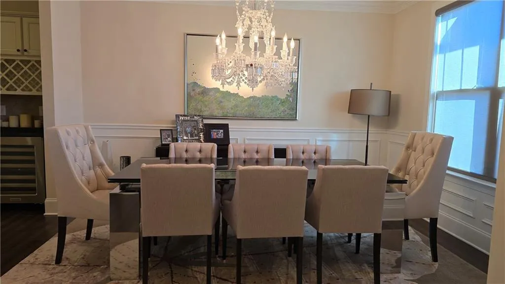 Dining area with a notable chandelier, plenty of natural light, wood finished floors, and ornamental molding