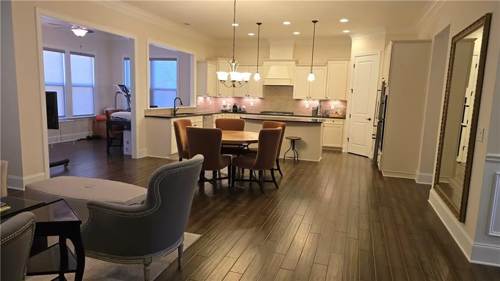 Dining space with baseboards, ornamental molding, recessed lighting, ceiling fan with notable chandelier, and dark wood-style floors