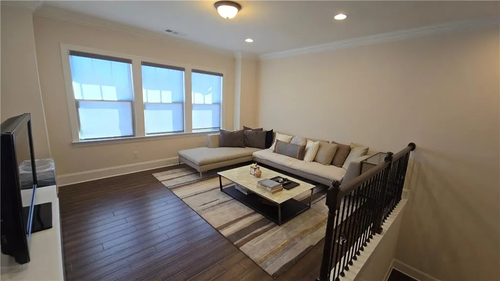 Living room featuring visible vents, wood finished floors, baseboards, and ornamental molding