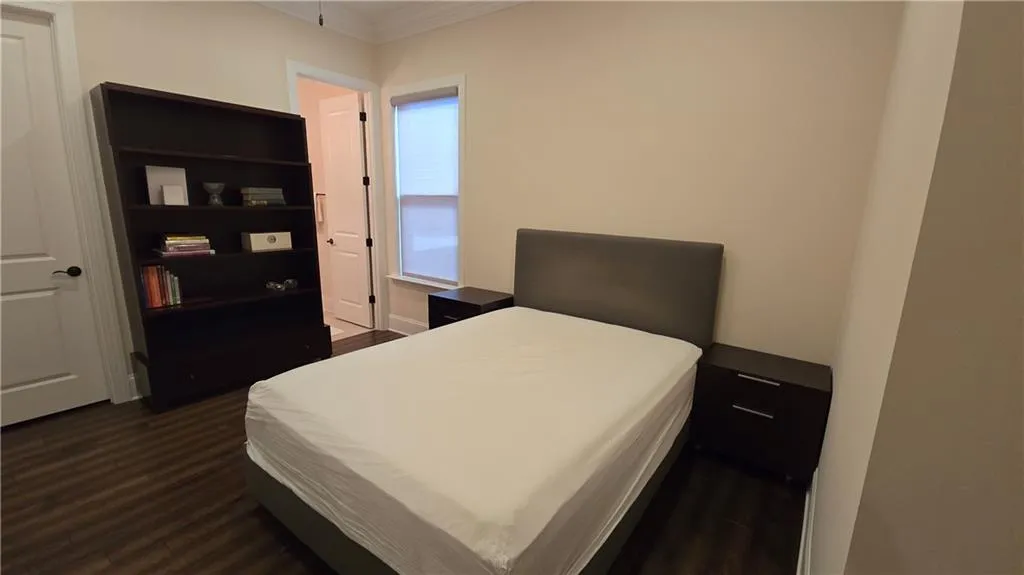 Bedroom with dark wood finished floors and ornamental molding