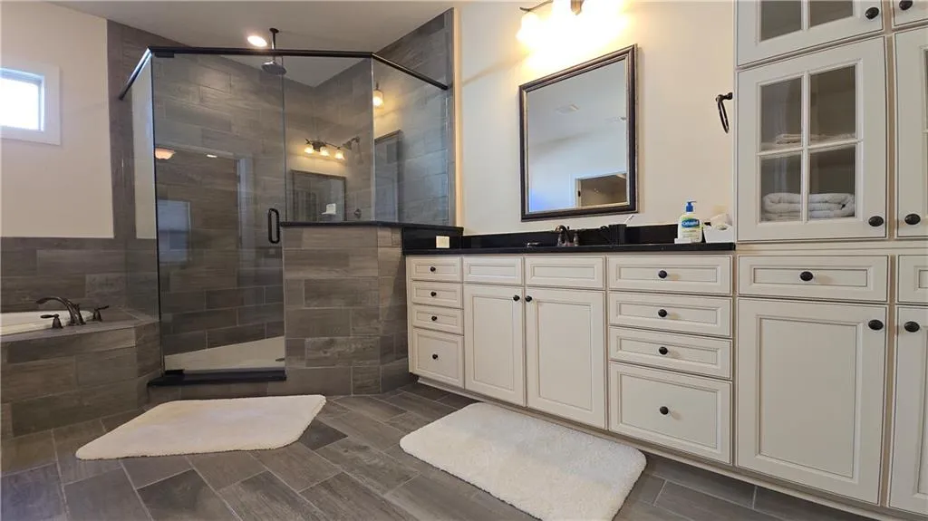 Bathroom featuring a stall shower, vanity, and a relaxing tiled tub