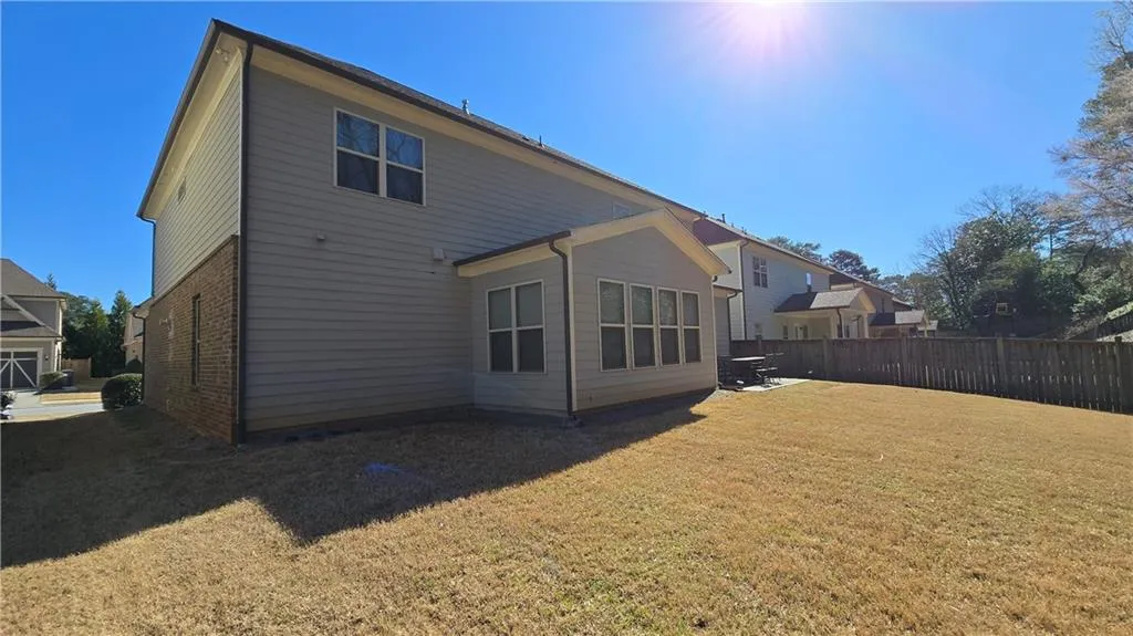Rear view of property featuring brick siding, a yard, and fence
