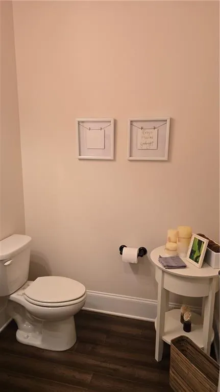 Half bathroom featuring toilet, baseboards, and wood finished floors