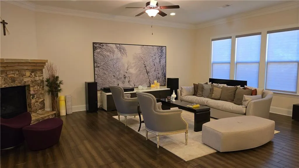Living room with ornamental molding, wood finished floors, visible vents, and ceiling fan
