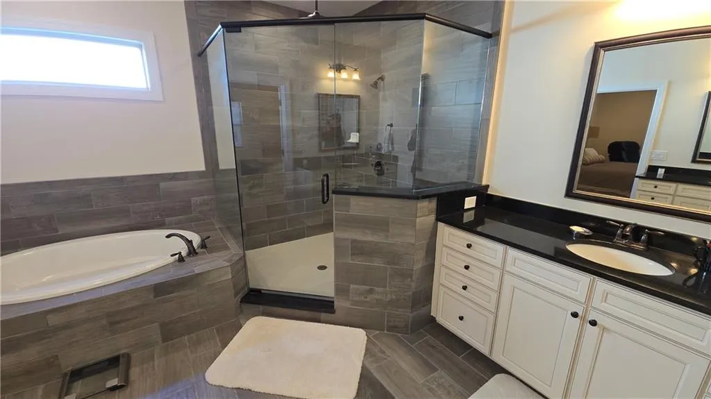 Bathroom featuring a bath, a stall shower, vanity, and ensuite bathroom