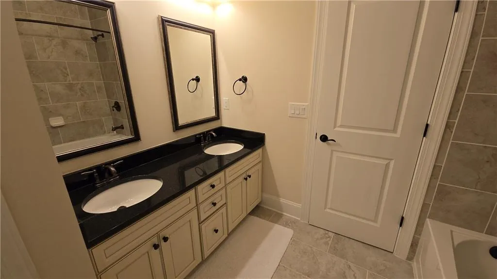 Bathroom with double vanity, baseboards, tile patterned floors, and a sink
