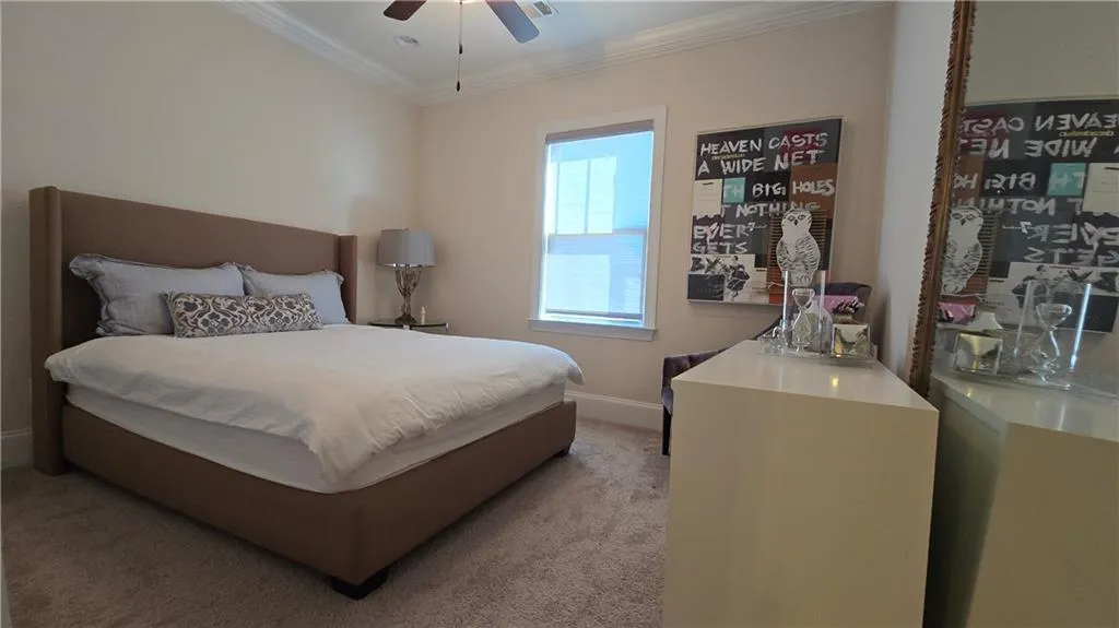 Bedroom with ceiling fan, baseboards, light carpet, and ornamental molding
