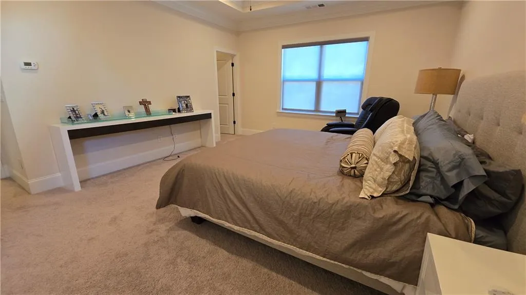 Carpeted bedroom with visible vents, baseboards, and ornamental molding