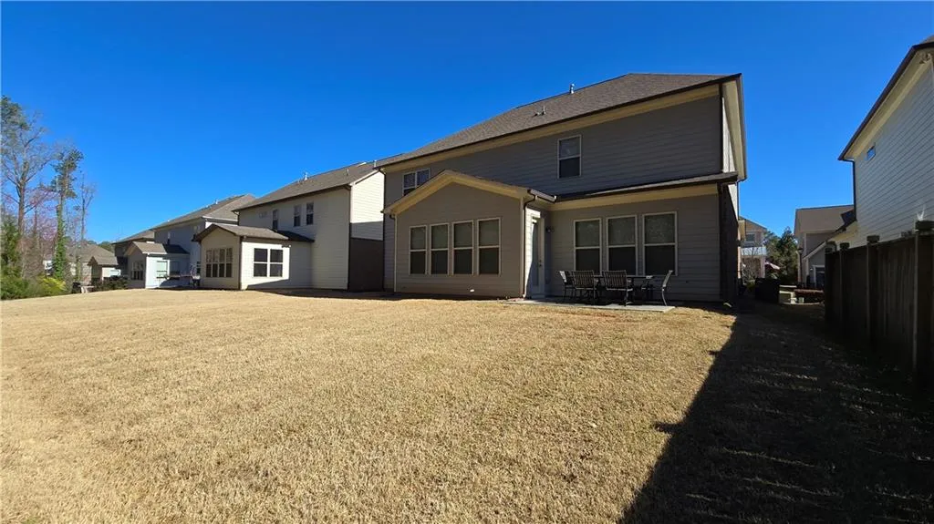 Rear view of house featuring a patio area, a lawn, and fence