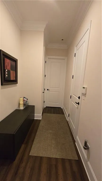 Hall with baseboards, ornamental molding, and dark wood-style flooring