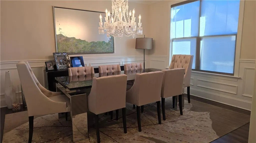 Dining space with a decorative wall, wainscoting, an inviting chandelier, and wood finished floors