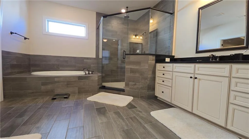 Bathroom with visible vents, a garden tub, vanity, a shower stall, and wood tiled floor