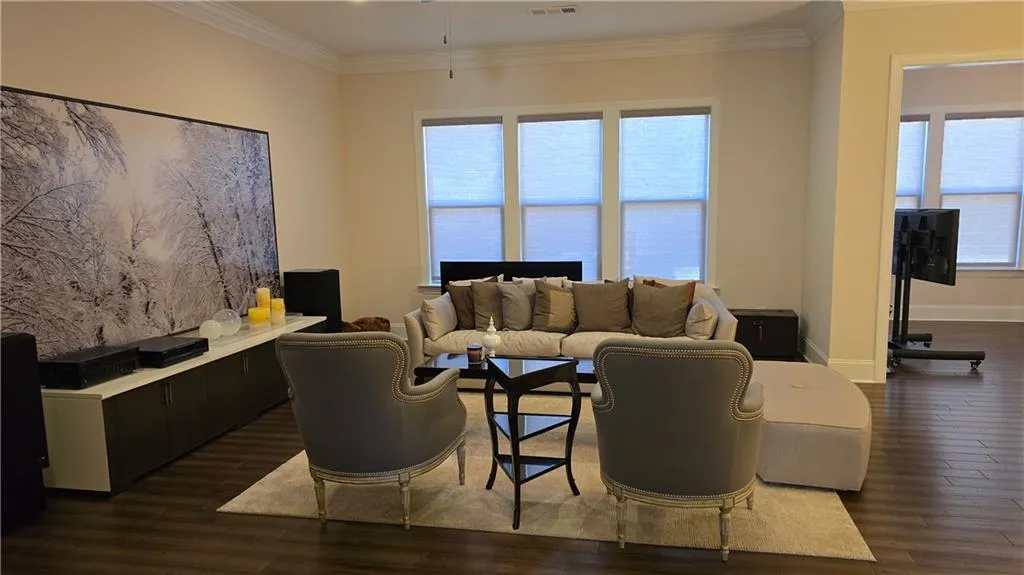Living room with crown molding, baseboards, dark wood-style flooring, and visible vents