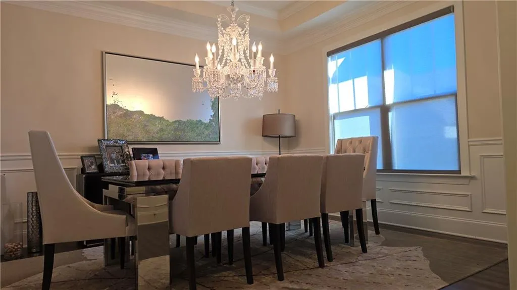 Dining room featuring a chandelier, a decorative wall, crown molding, and a tray ceiling