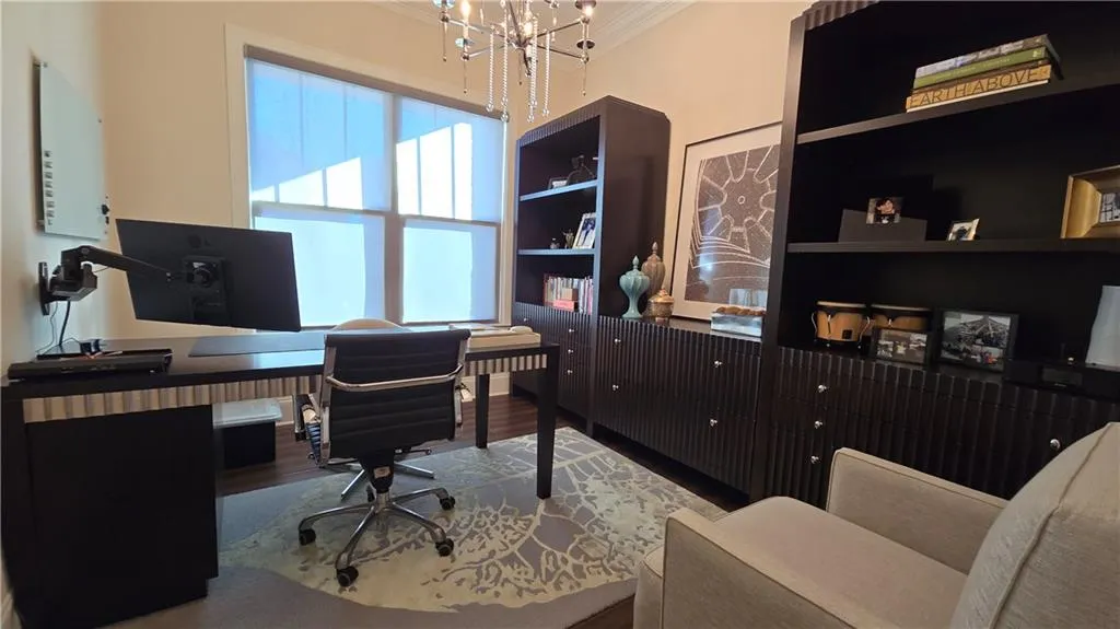 Office space featuring built in features, ornamental molding, an inviting chandelier, and wood finished floors