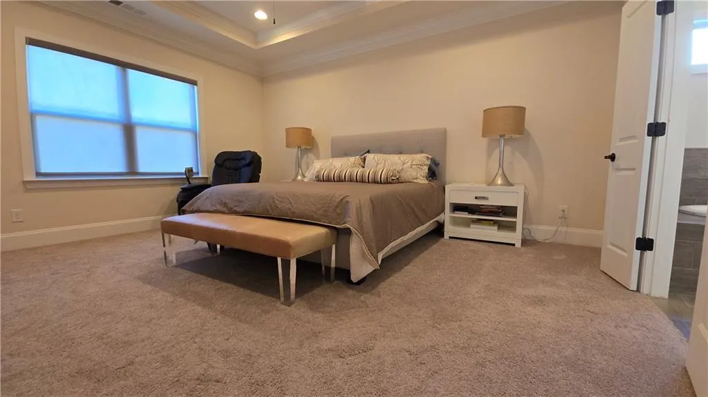 Carpeted bedroom featuring crown molding, recessed lighting, baseboards, and a raised ceiling