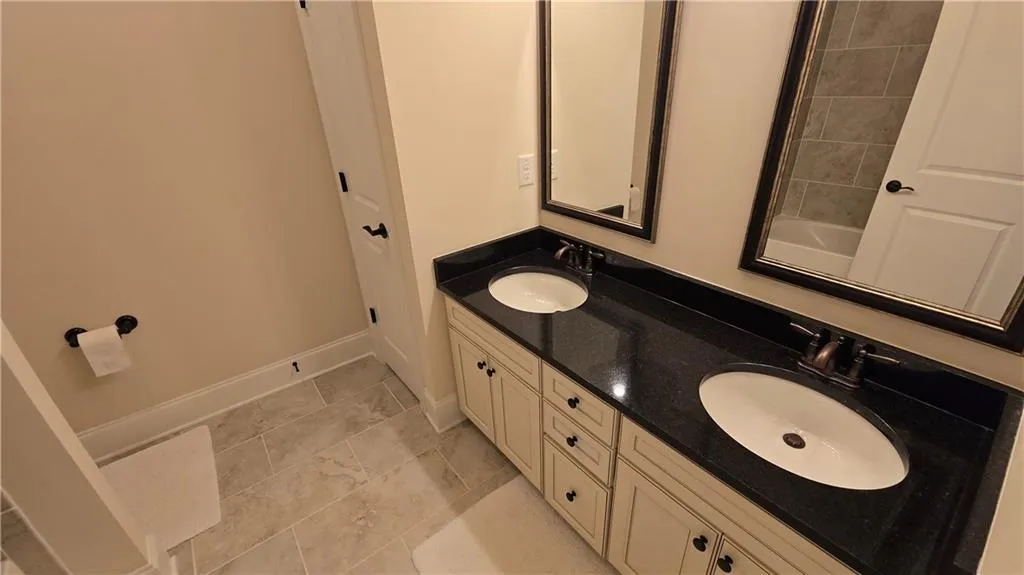 Full bath with double vanity, baseboards, and a sink