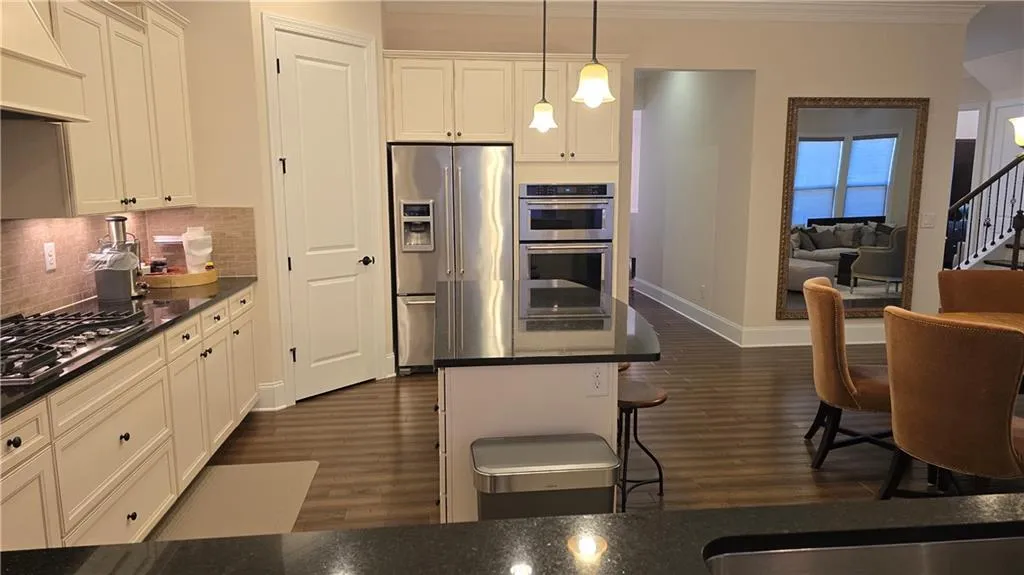 Kitchen featuring dark countertops, appliances with stainless steel finishes, dark wood-style flooring, and custom range hood