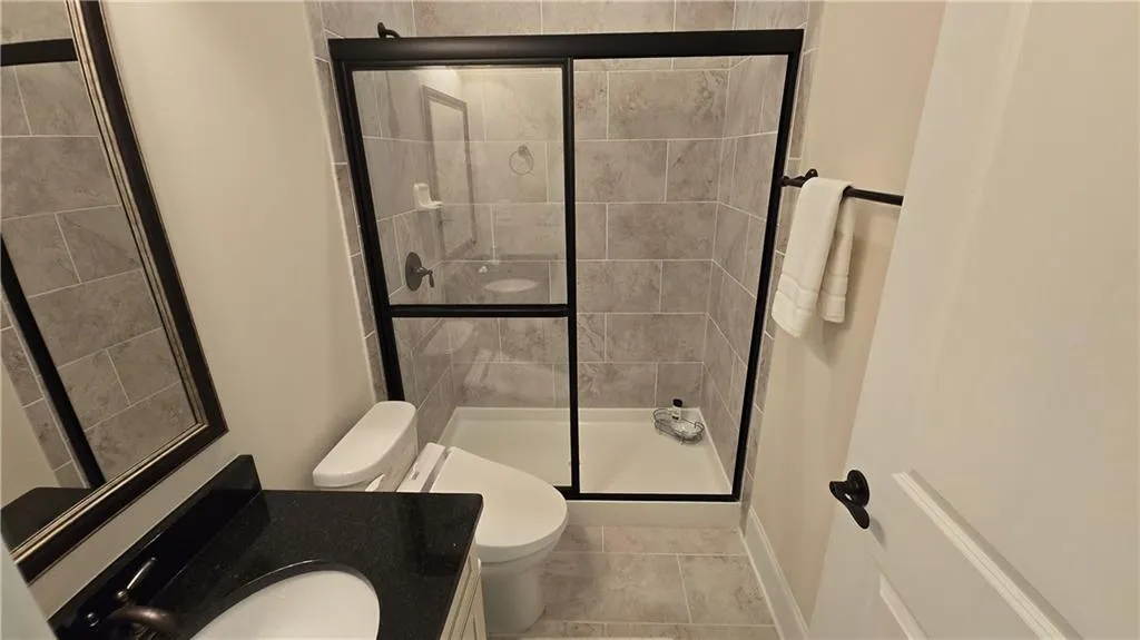 Full bath featuring tile patterned flooring, a stall shower, toilet, and vanity