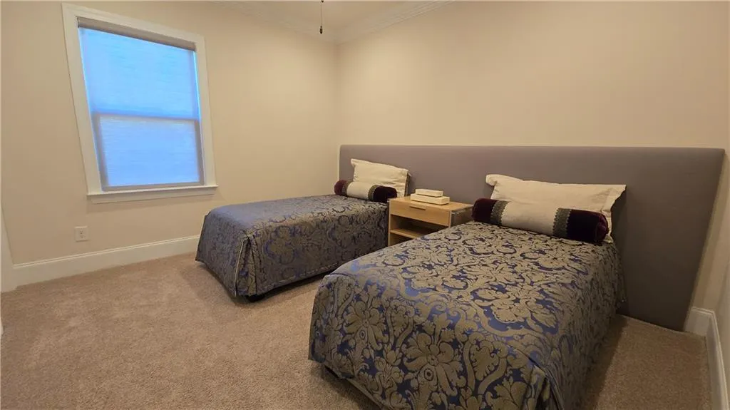 Carpeted bedroom with crown molding and baseboards