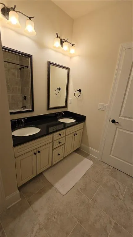 Bathroom featuring double vanity, baseboards, and a sink