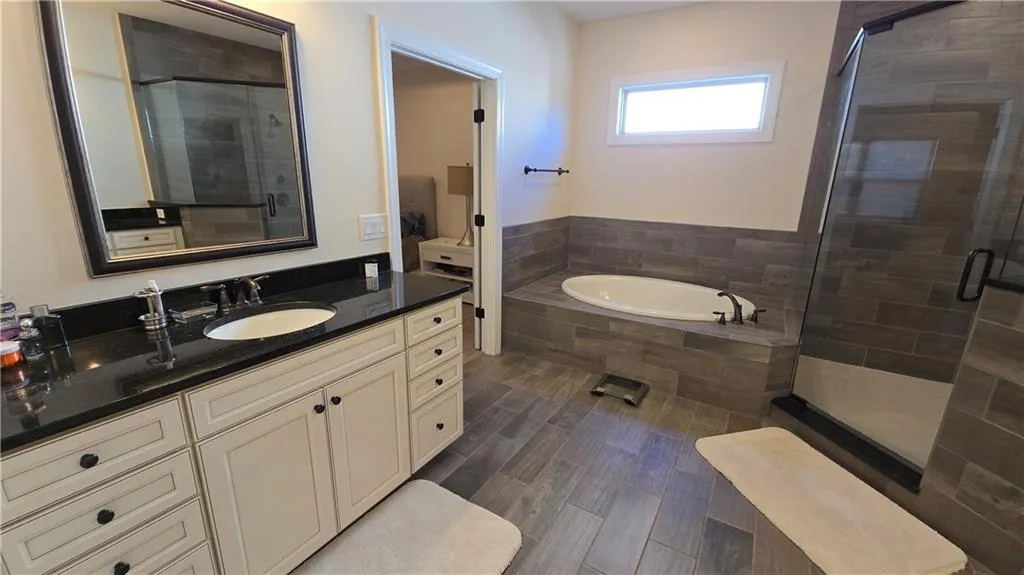 Bathroom featuring a stall shower, vanity, a garden tub, and wood finished floors
