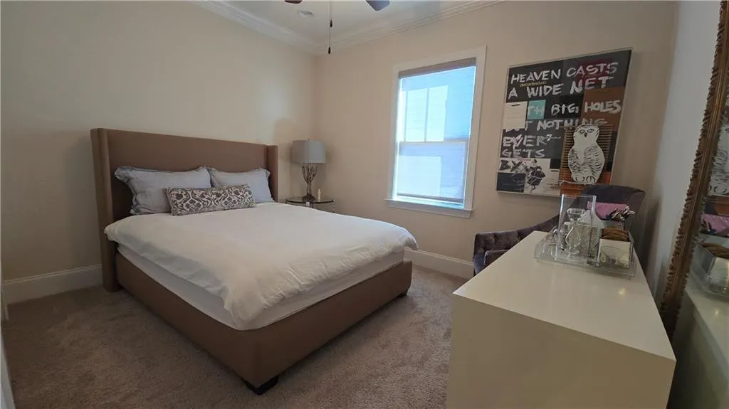 Bedroom featuring ceiling fan, crown molding, baseboards, and light carpet