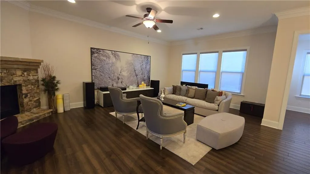 Living room with visible vents, crown molding, baseboards, ceiling fan, and dark wood-style floors