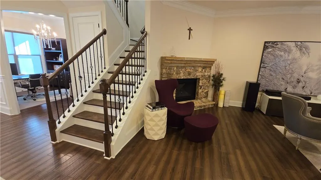 Staircase featuring wood finished floors, baseboards, an inviting chandelier, a fireplace, and ornamental molding