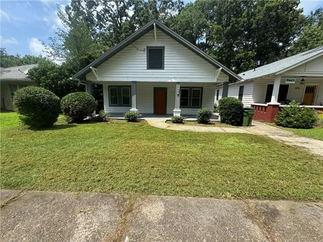 Gabled exterior with white siding, charcoal trim, and an orange entry door