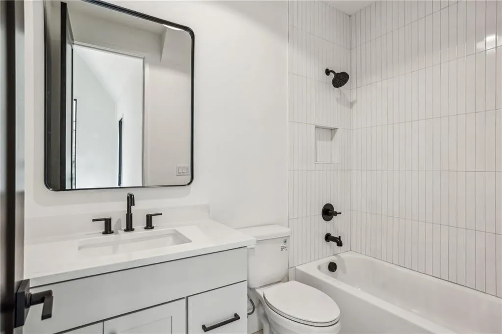 Full bathroom featuring tiled shower / bath combo, vanity, and toilet