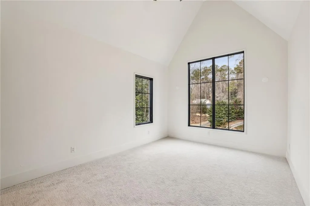Carpeted empty room with high vaulted ceiling