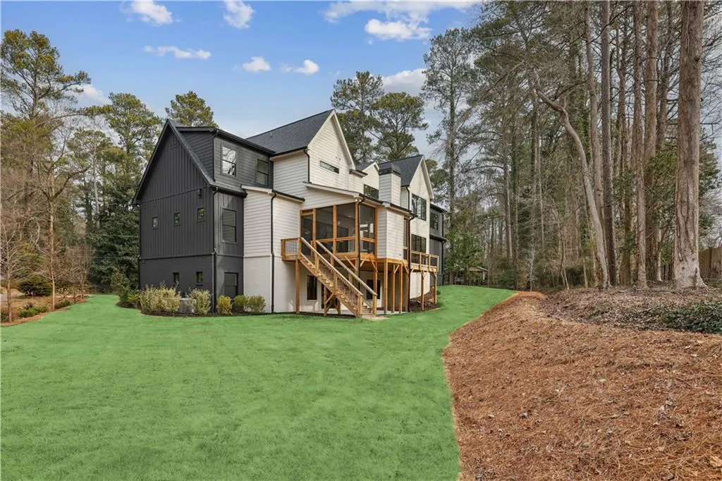 Back of property featuring a lawn, a sunroom, and a deck