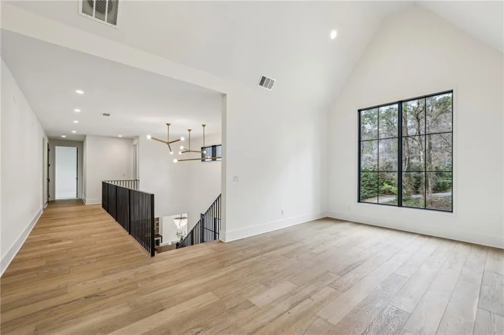 Unfurnished room featuring a chandelier, light hardwood / wood-style floors, and high vaulted ceiling