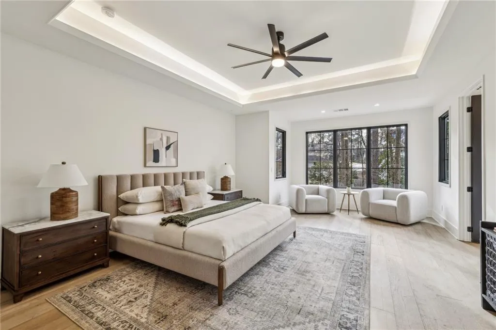 Bedroom with a raised ceiling, ceiling fan, and light wood-type flooring