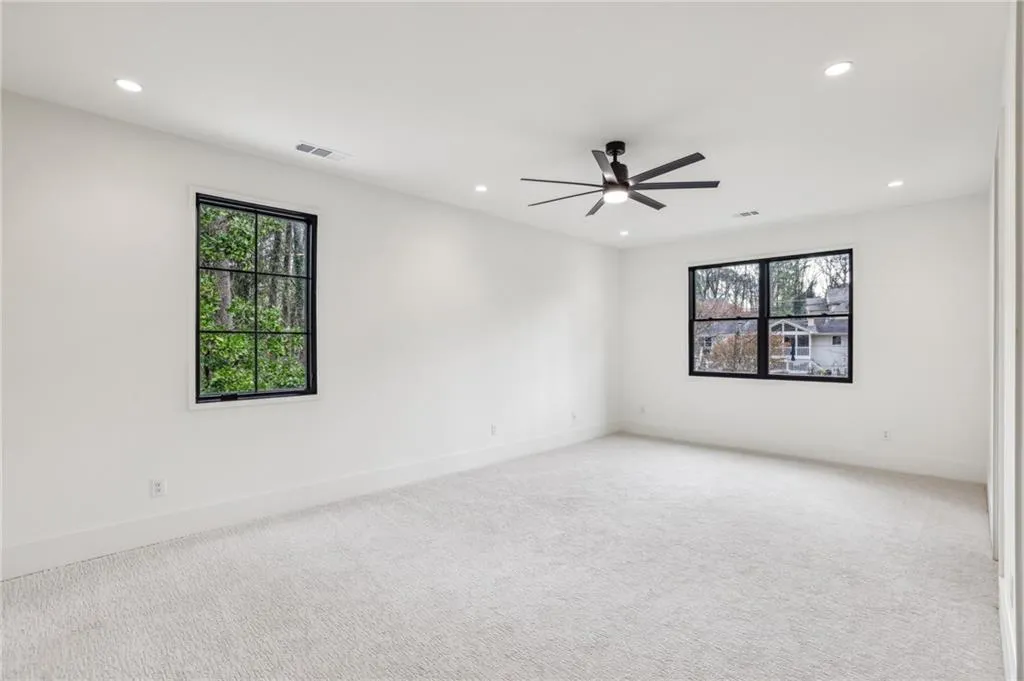 Carpeted empty room with plenty of natural light and ceiling fan
