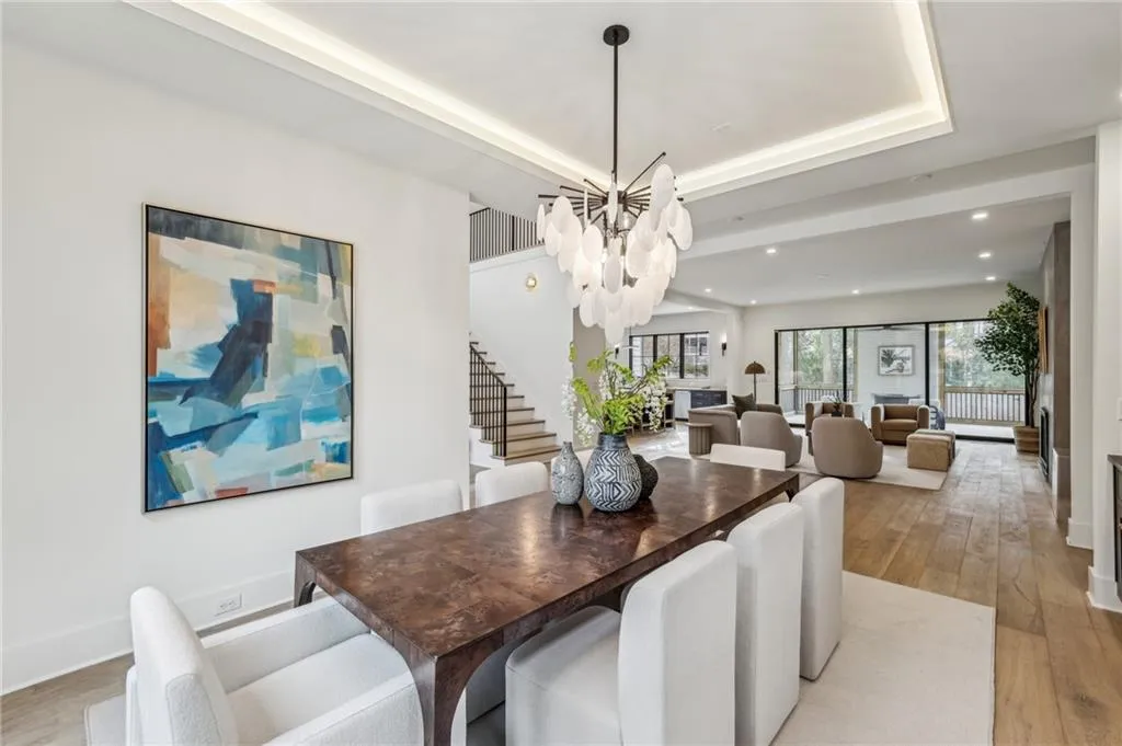 Dining room featuring a raised ceiling, a healthy amount of sunlight, a chandelier, and light wood-type flooring