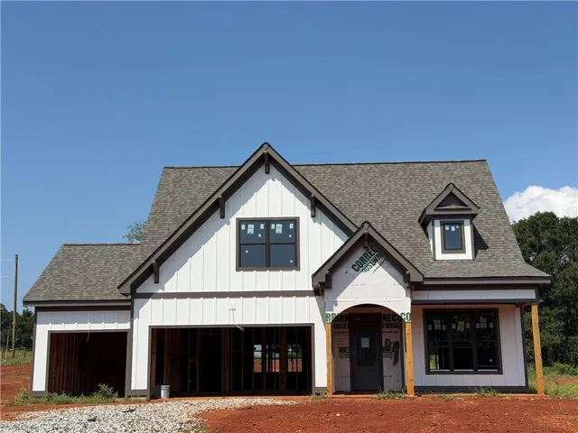 Two-story exterior with board and batten siding, dark framed windows, an attached two-car garage, and a gabled roofline