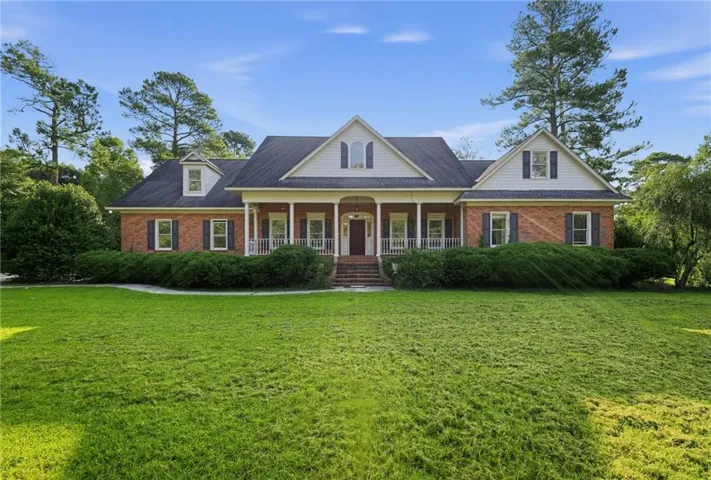 Traditional brick exterior with white trim, covered front porch, dormer windows, and dark shutters