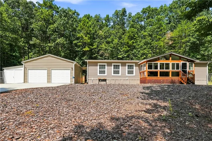 Exterior with tan siding, dual attached garage, and a screened-in porch with wood railing