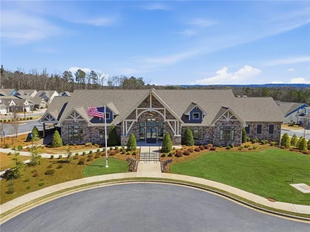 Stone and timber frame building with a prominent central entrance, gabled rooflines, and a manicured lawn
