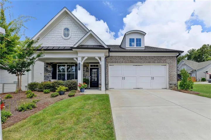 Traditional exterior featuring a covered porch with white columns, stone veneer, and shake siding