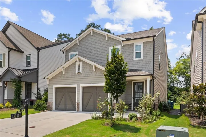 Two-story residence featuring a two-car garage with carriage-style doors, a gabled roofline, and mixed exterior siding