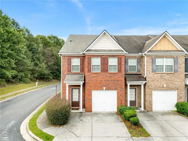 Brick facade townhome featuring a single-car garage and a paved driveway
