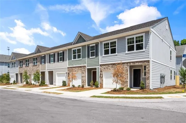 Contemporary townhome with stone and siding exterior, front-facing garage, and covered entry