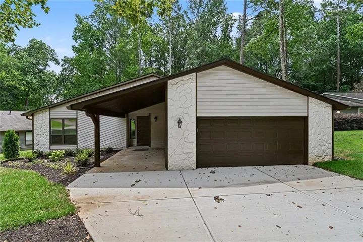 Ranch-style residence featuring a prominent two-car garage with a dark brown door